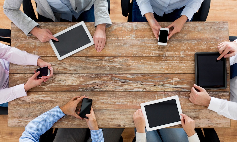 business, people, technology and team work concept - close up of creative team with smartphones and tablet pc computers sitting at table in office